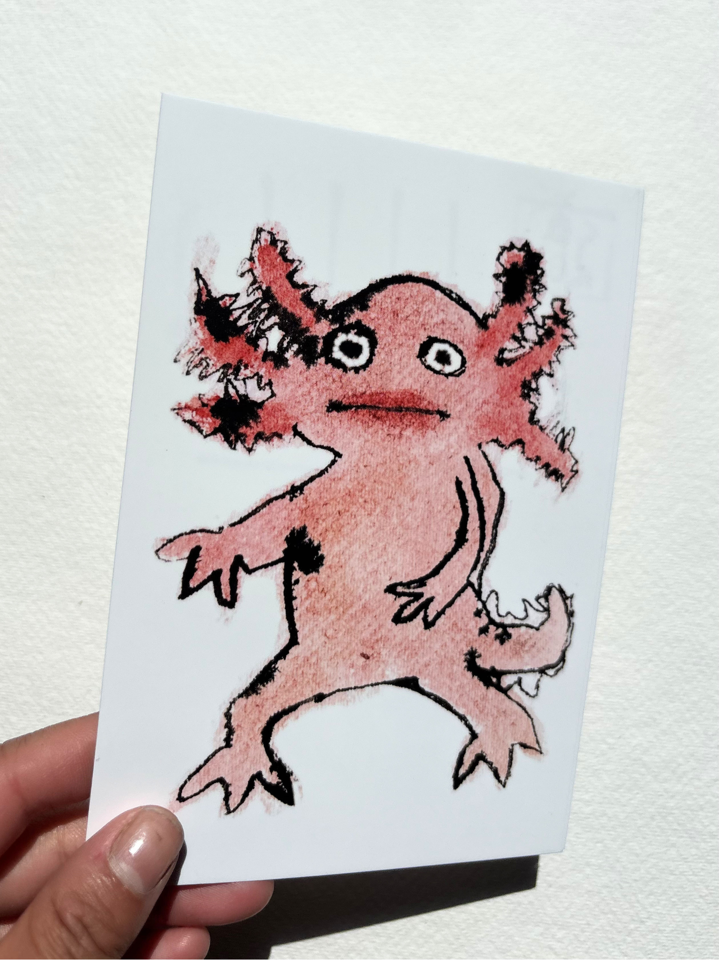 A6 postcard featuring a vivid hand draw watercolour illustration of a cartoon Axolotl.