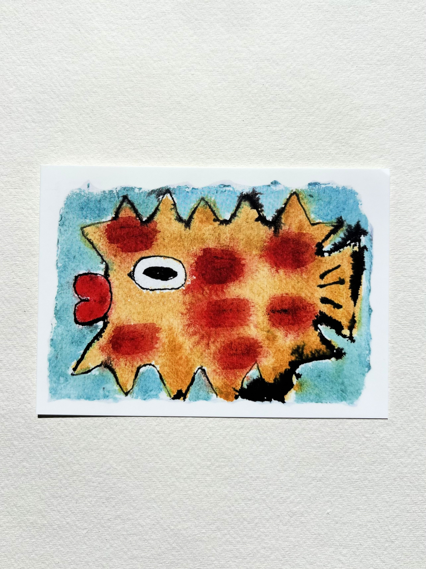 A6 postcard featuring a vivid hand drew watercolour illustration of a puffer fish with blue background.