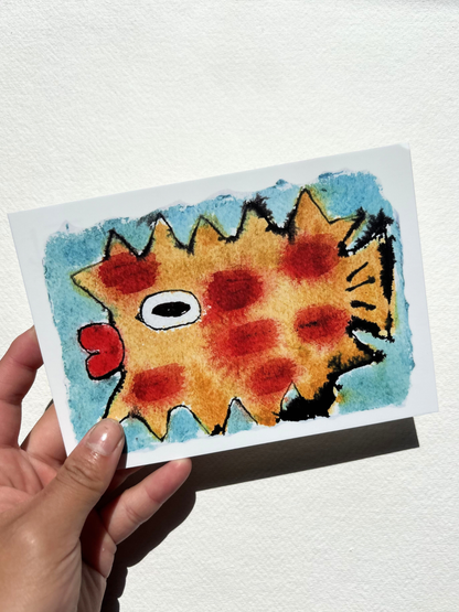 A6 postcard featuring a vivid hand drew watercolour illustration of a puffer fish with blue background.